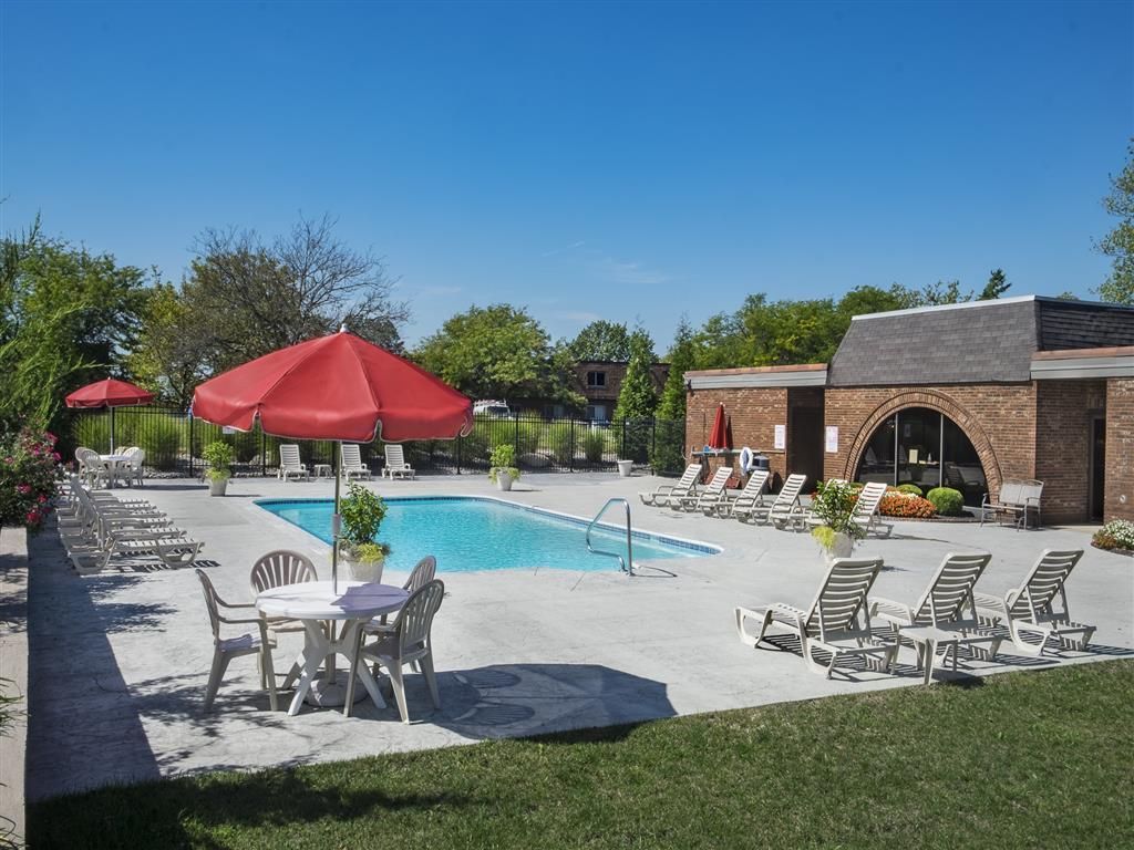 Outdoor apartment community pool with lounge chairs and red umbrellas at Shadow Hill, offering townhomes in Sharonville, OH.