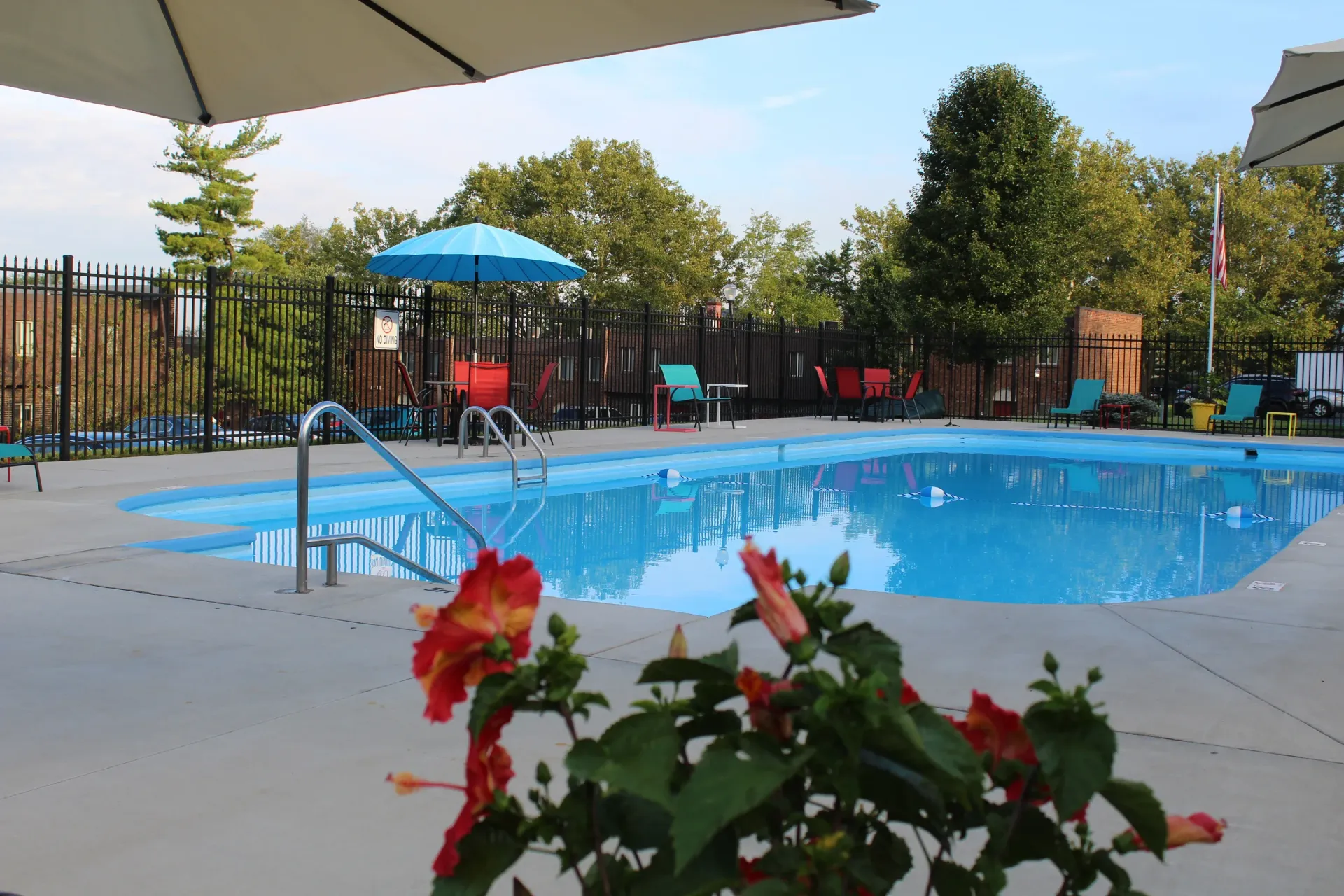 Outdoor apartment community pool with blue water, lounge chairs, umbrellas, and a surrounding fence at Shadow Hill, offering townhomes for rent in Sharonville, OH.