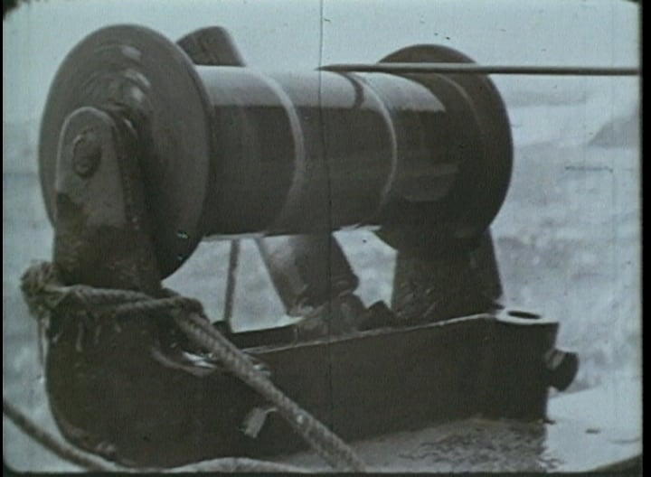 A black and white photo of a machine with a rope attached to it.