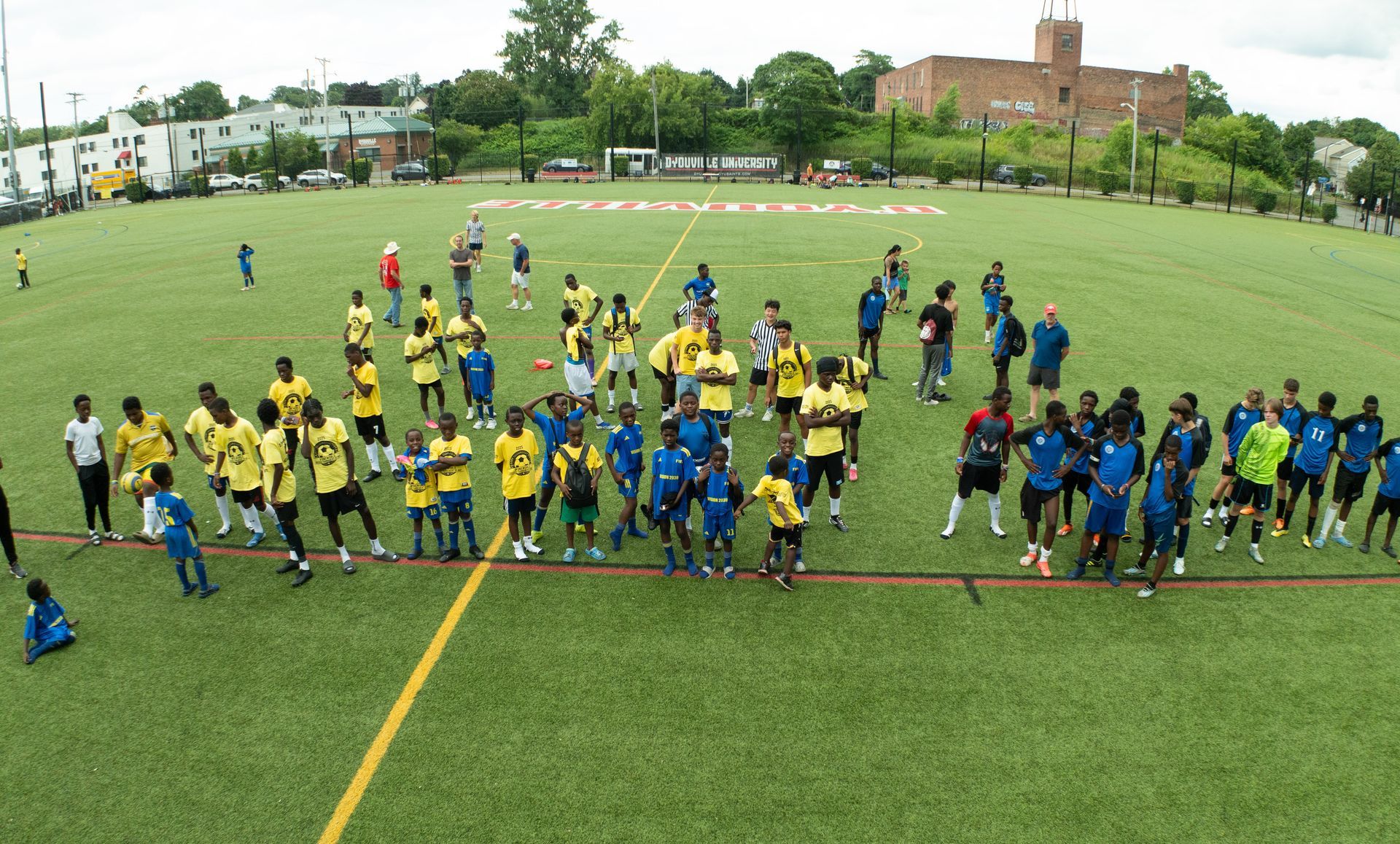 Large group of players in yellow and blue jerseys lined up on a soccer field after a match