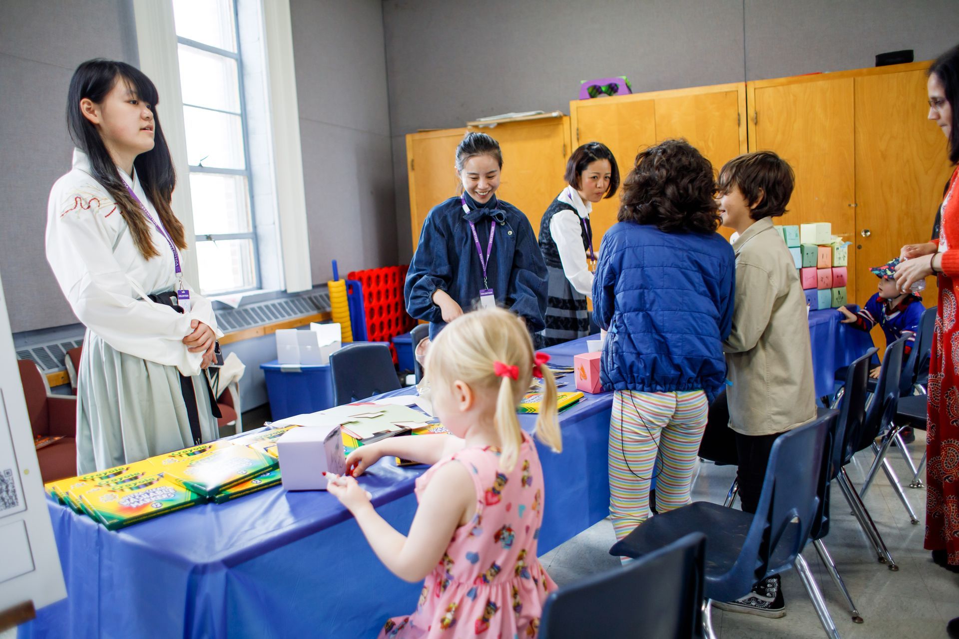 Teacher speaking to children at a classroom table during a hands-on activity