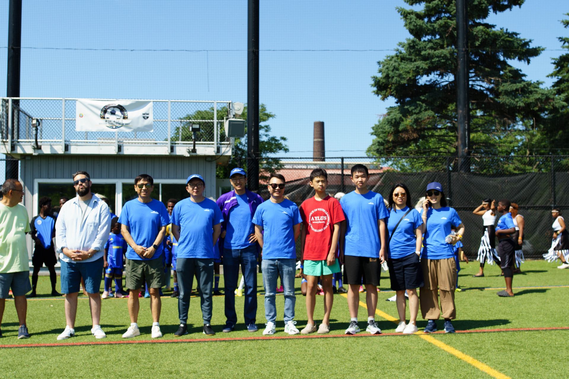 People in blue shirts standing in a line on a sports field under a clear sky