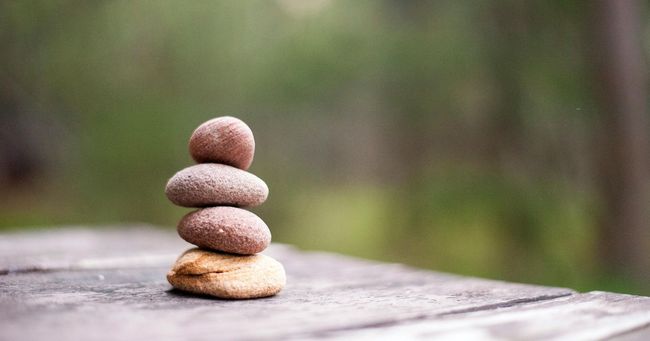 Stacked pebbles balanced on a wooden surface with a blurred green background