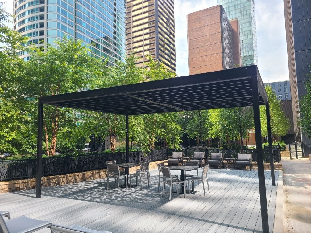 There is a pergola with tables and chairs underneath it.