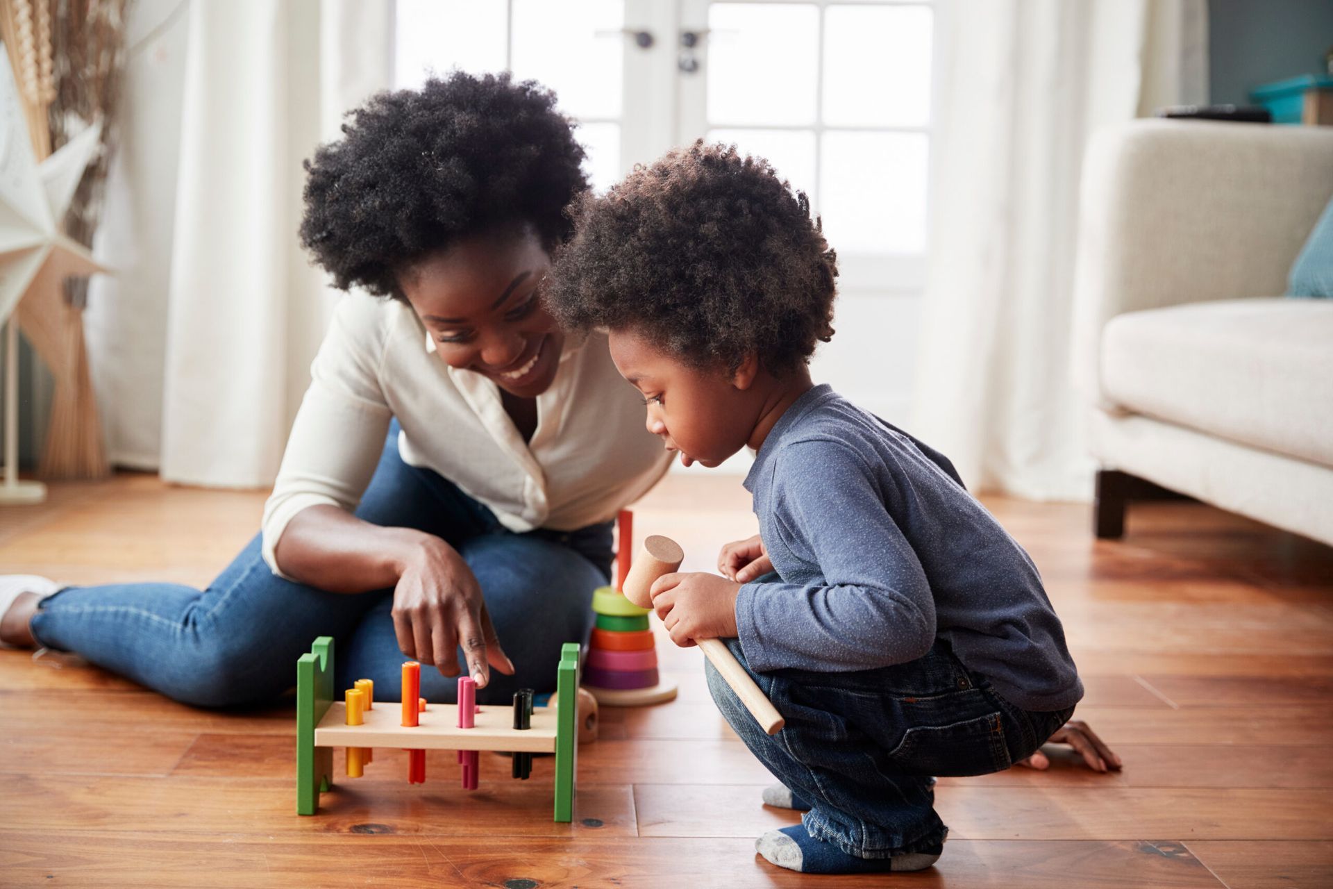Femme et enfant jouant avec un jouet en bois sur un plancher en bois dans un salon.