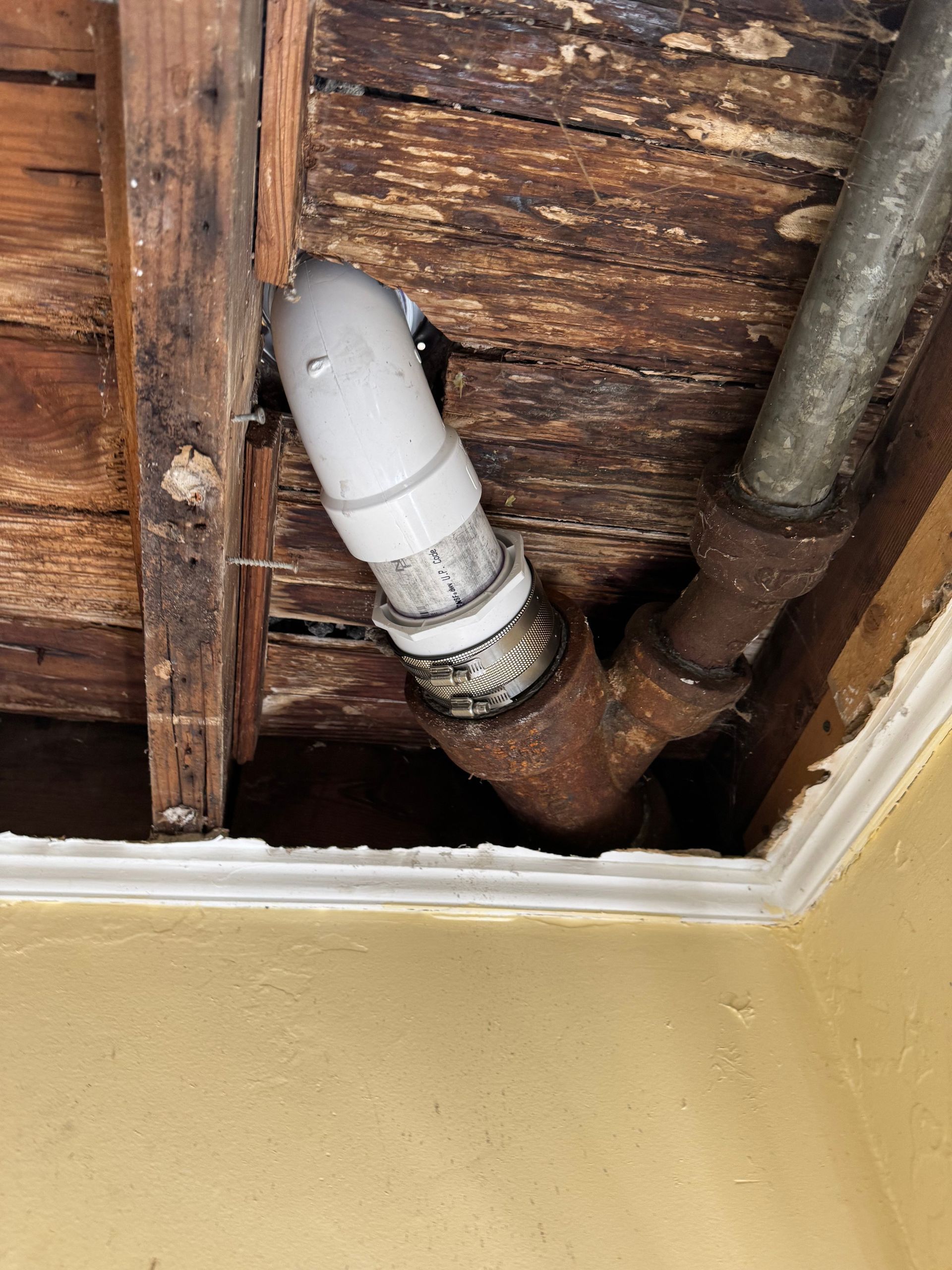 A pipe is coming out of a hole in the ceiling.