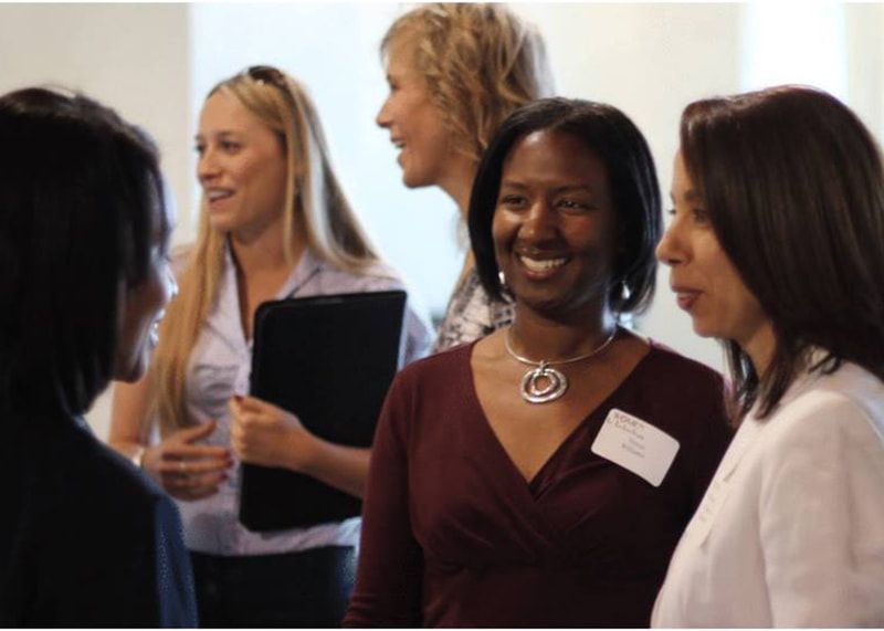 A group of women are standing in a circle talking to each other