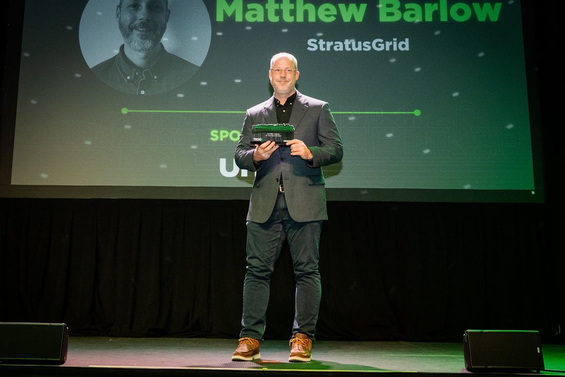 A man in a suit is standing on a stage holding a microphone.