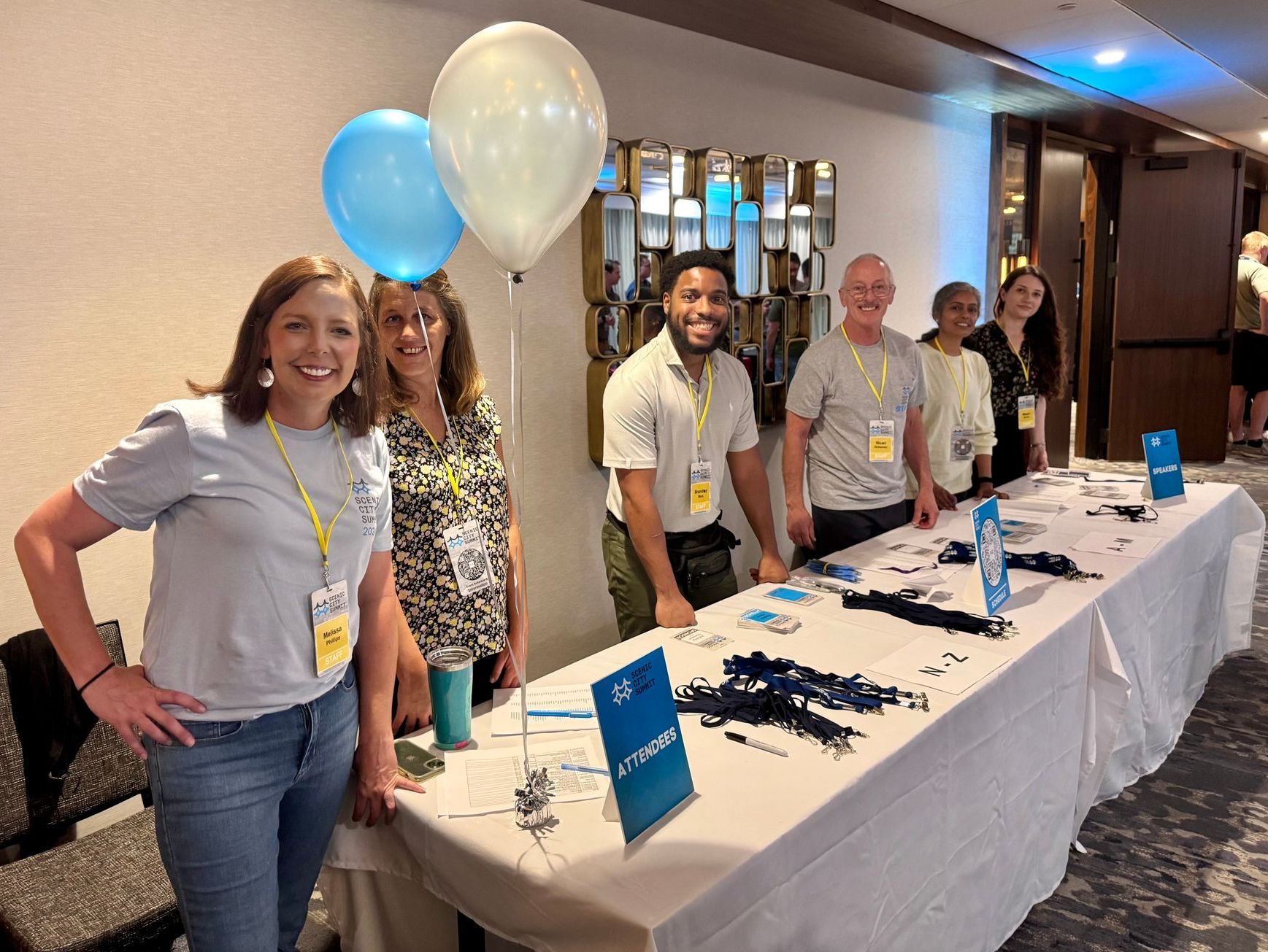 A group of people are standing around a table with balloons.