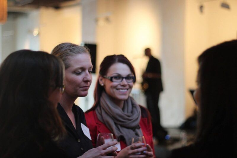 A woman wearing glasses is talking to two other women