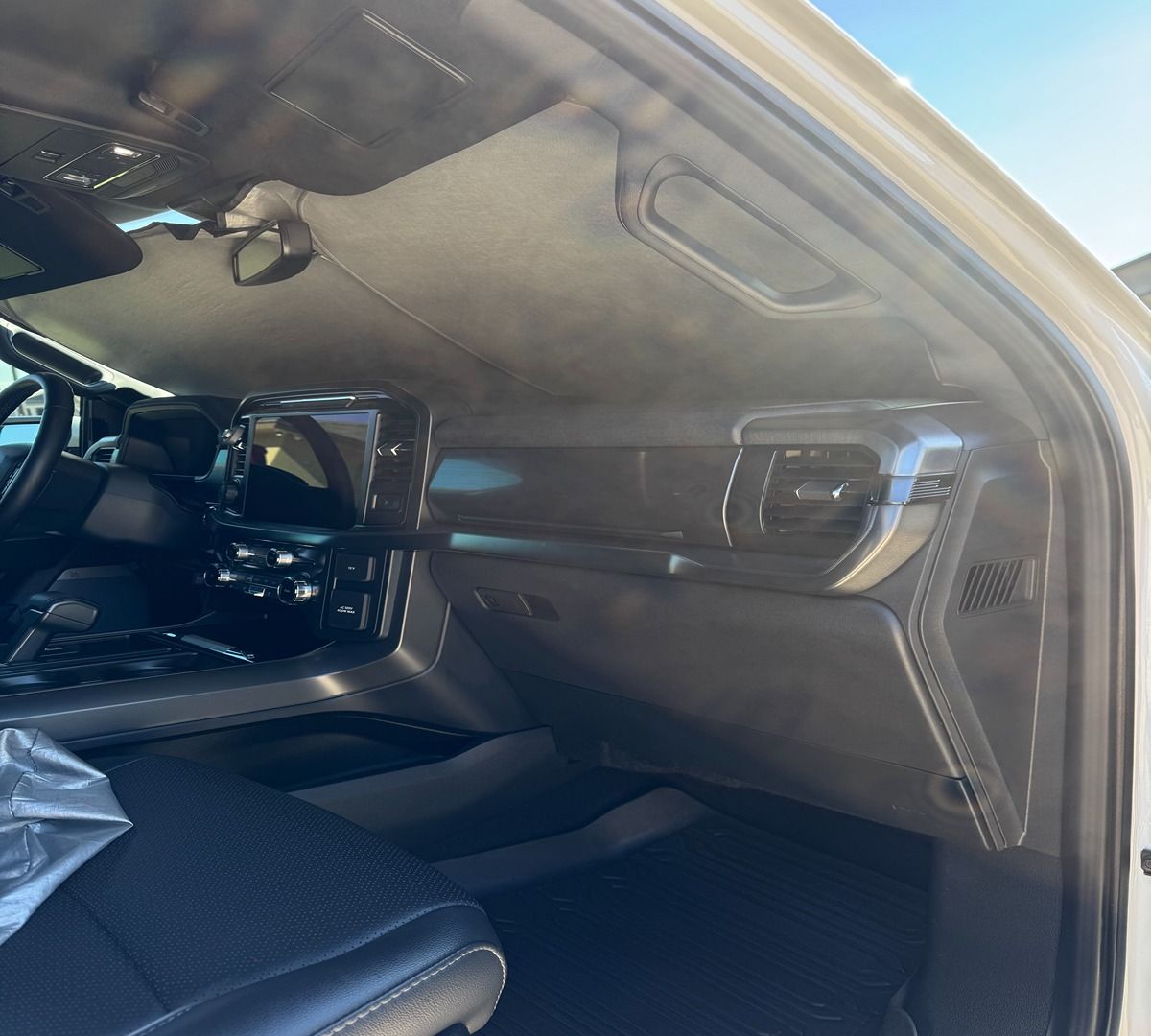Passenger side interior of a dark-toned vehicle, showing the dashboard, glove box, and seat.