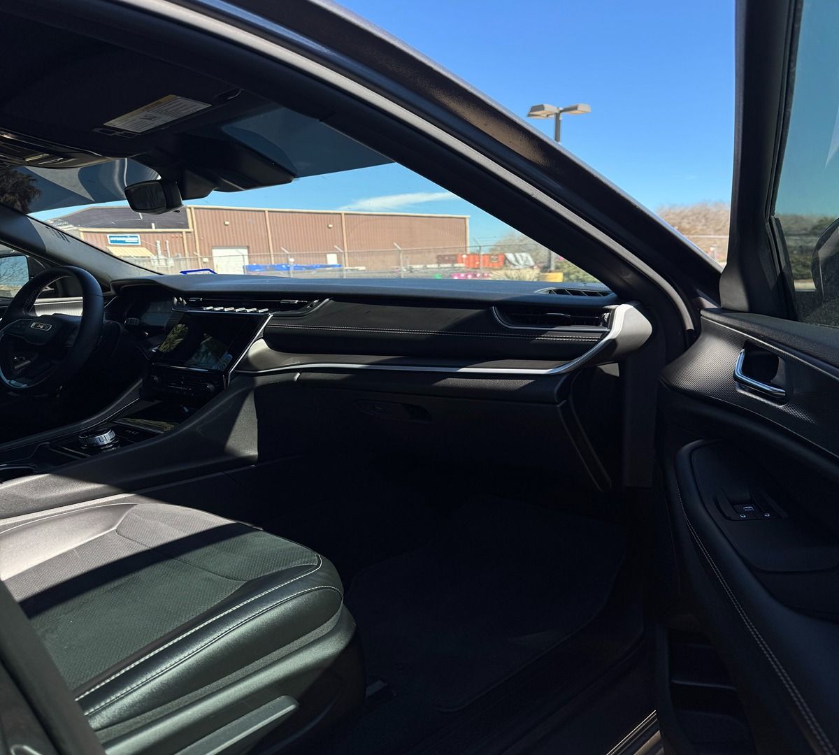The interior view from the passenger side of a car showing the dashboard, steering wheel, and black leather seats.