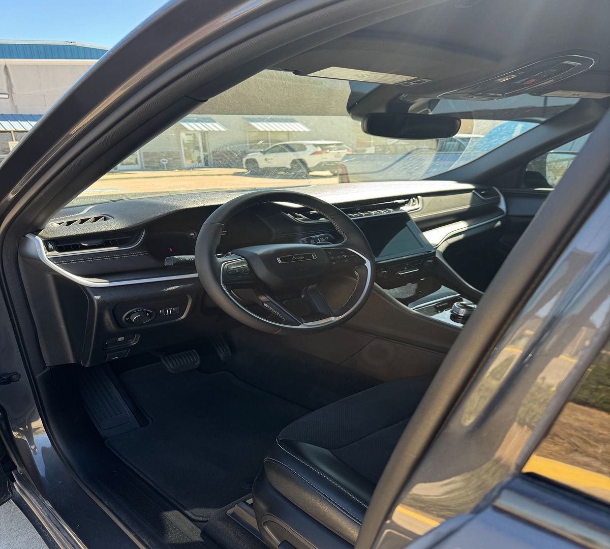 Interior view of a modern dark gray SUV from the open driver's side door, showing the dashboard and steering wheel.