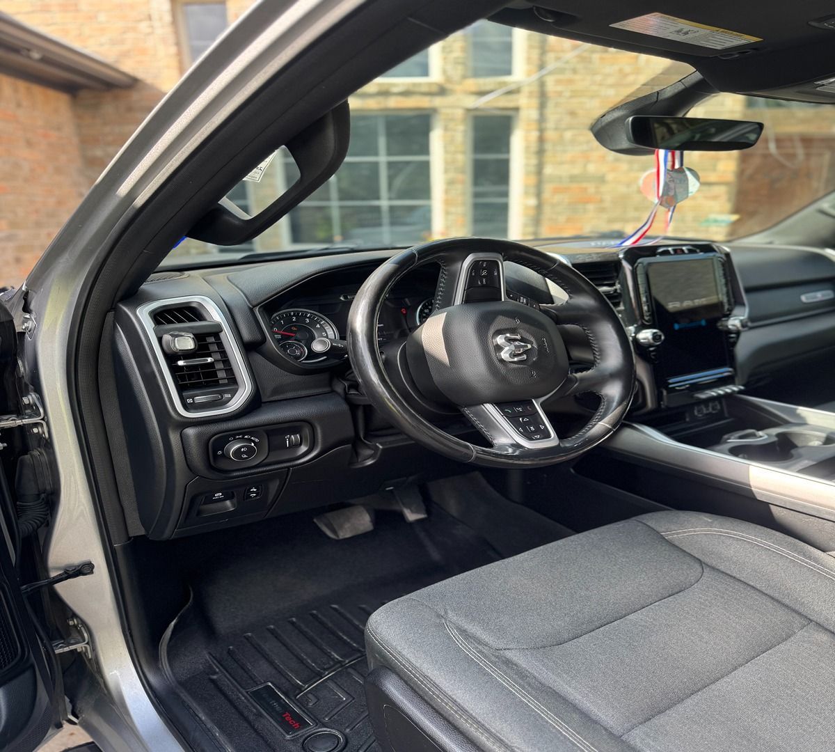 Interior view of a modern truck featuring a dark gray dashboard, leather-wrapped steering wheel, and gray fabric seats.