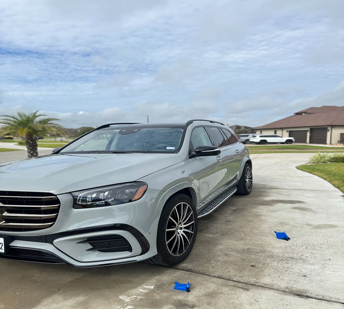 A light gray SUV parked in a residential driveway on a cloudy day.