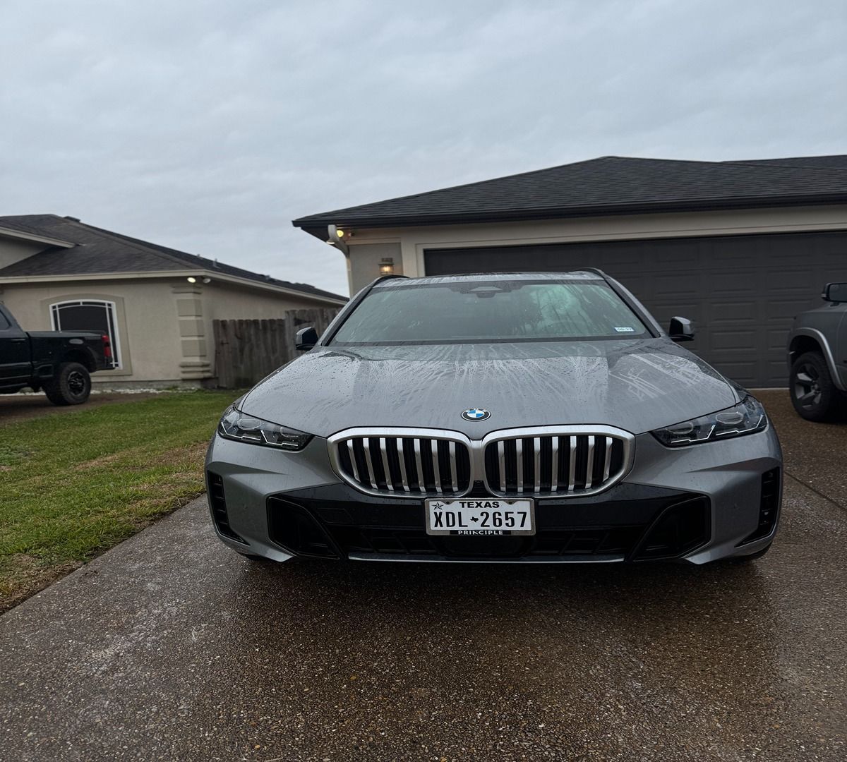 A gray BMW parked on a residential driveway on an overcast day.