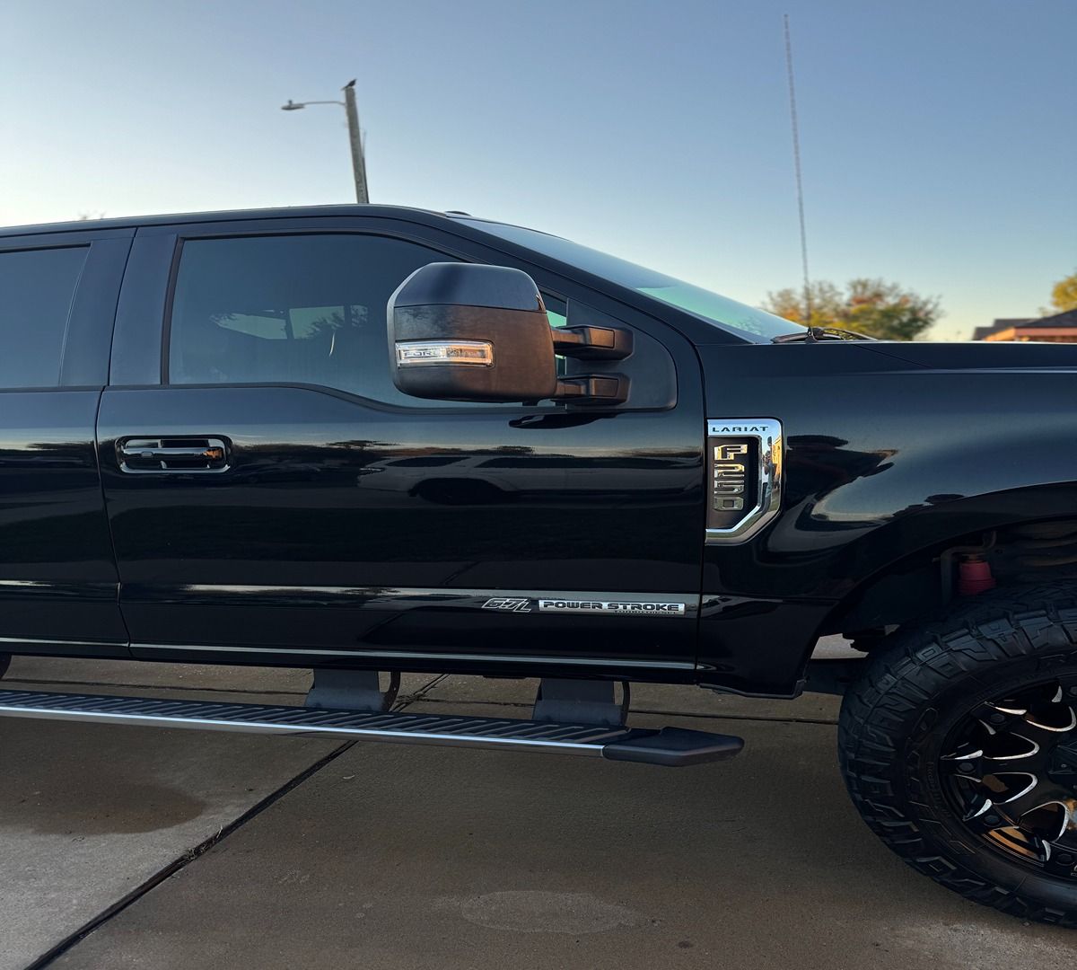 Side profile of a black Ford Super Duty truck parked on a concrete surface.