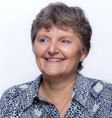 A woman is smiling and wearing a leopard print shirt.