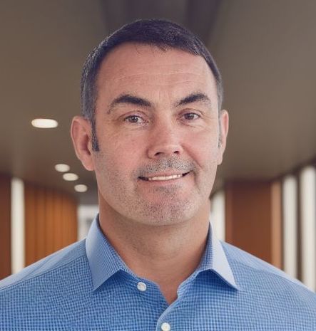 A man in a blue shirt is smiling for the camera.