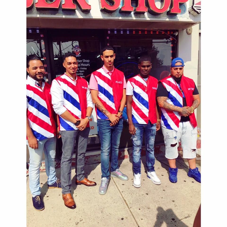 Five men in red, white, and blue striped shirts stand outside a shop.