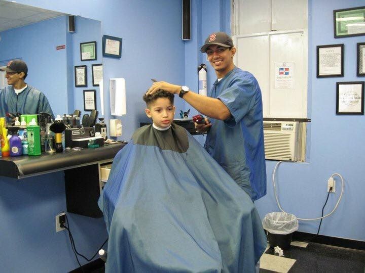Hairdresser cutting a child's hair in a blue barbershop with a mirror and grooming tools nearby