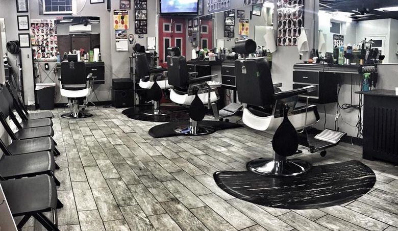 Empty modern hair salon with black styling chairs, mirrors, and wood-look flooring