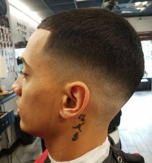 Close-up of a fresh fade haircut with a neck tattoo in a barbershop.