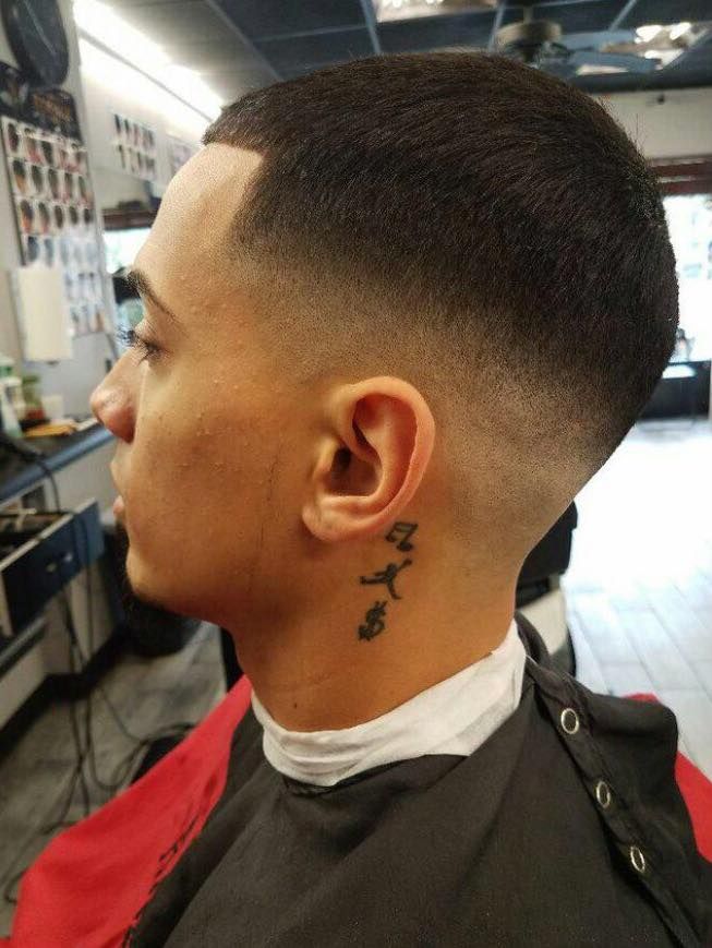 Profile view of a man with a faded haircut and neck tattoo in a barber shop chair