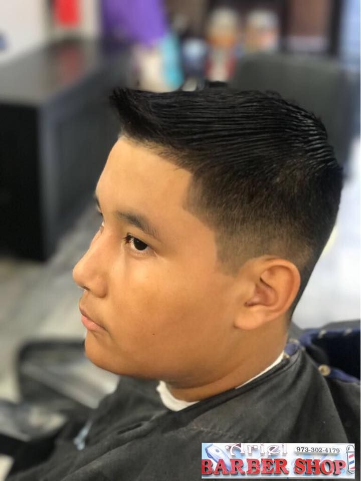 Side profile of a fresh fade haircut in a barbershop, with a blurred barber chair background.