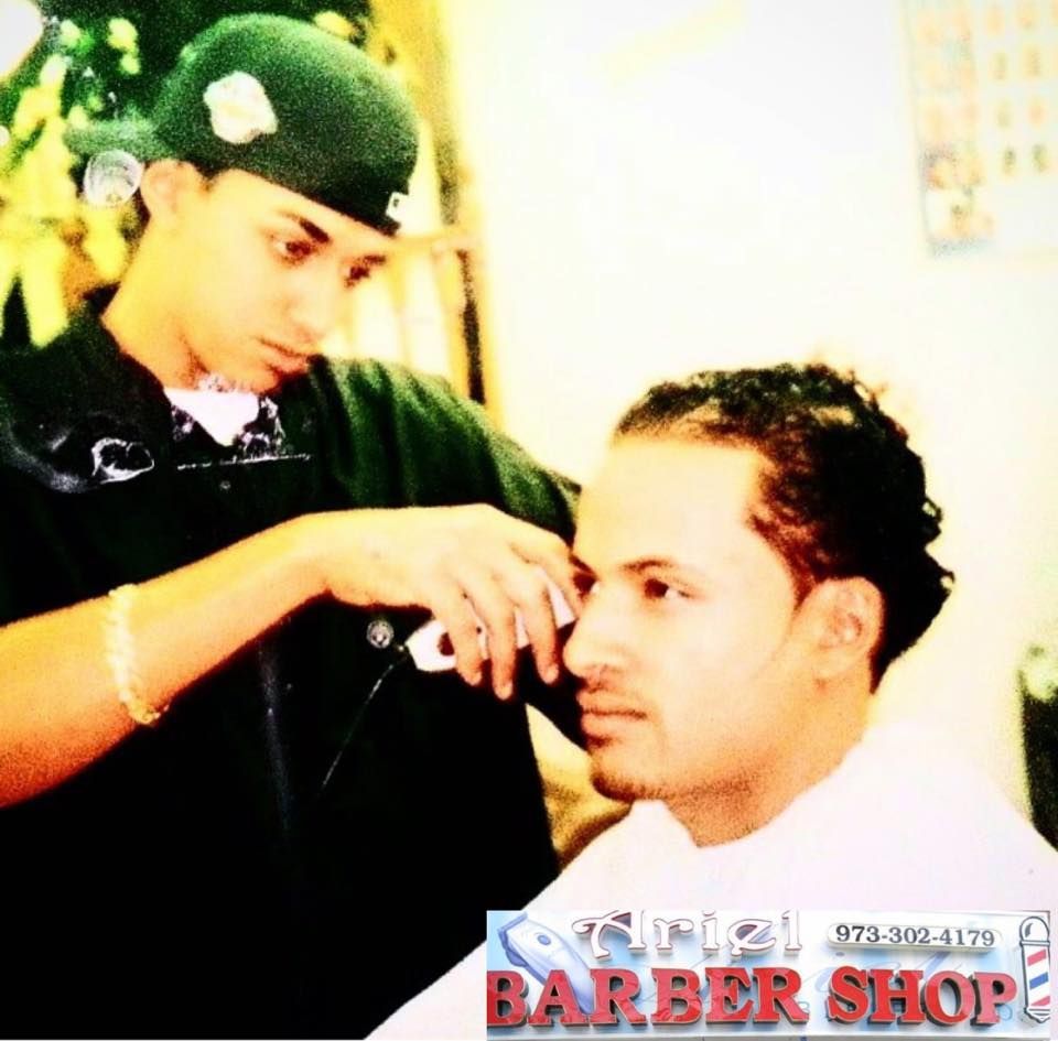 Barber trimming a seated customer's hair in a bright barbershop