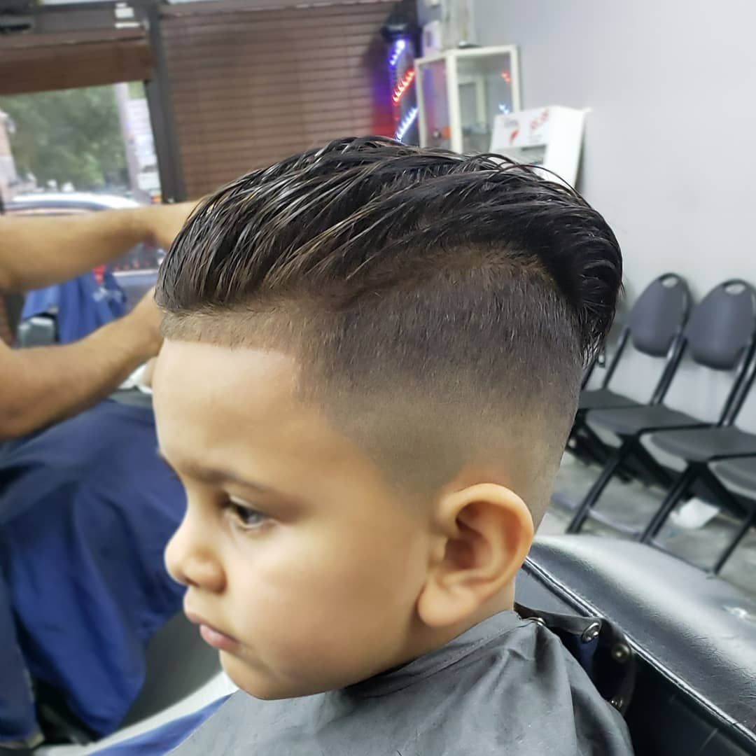 Young child with a neat fade haircut sitting in a barber chair at a salon