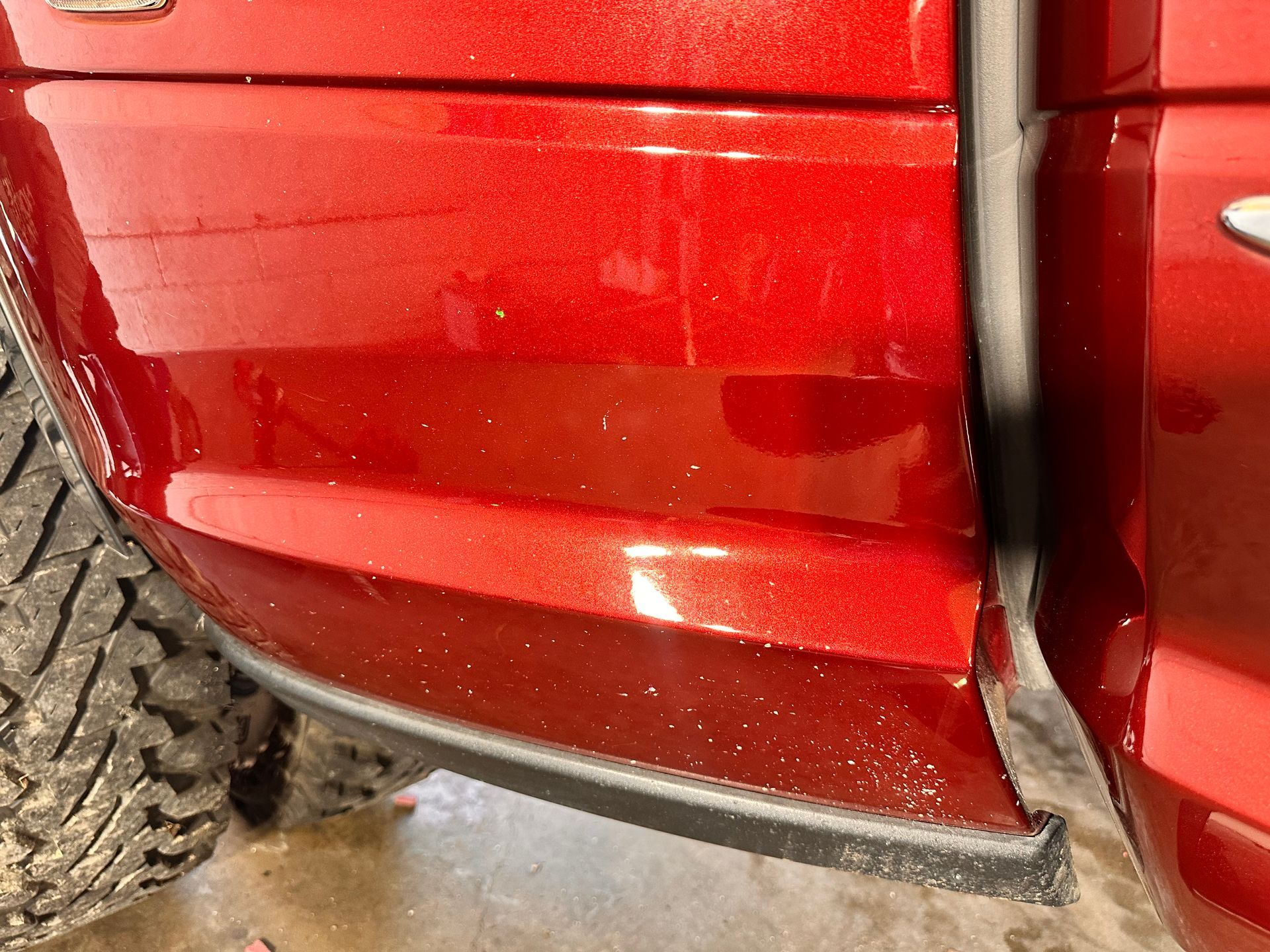 Red truck's side panel with a black rubber strip at the bottom.