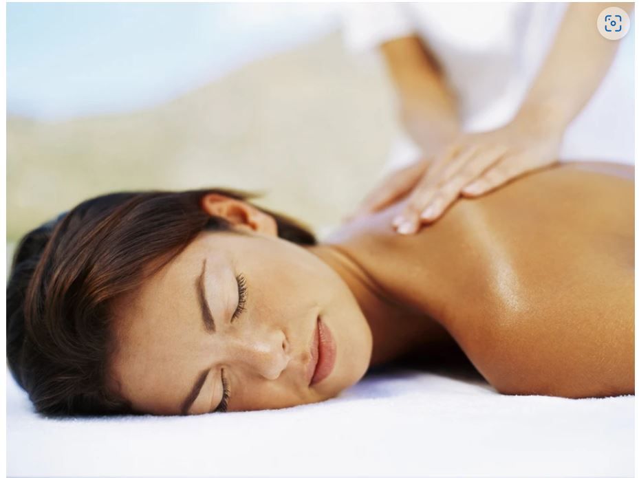 A person lying on their stomach on a massage table while receiving a back massage with their eyes closed.