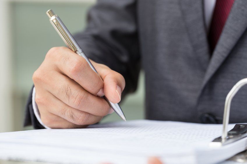 business attorney writing on documents at desk