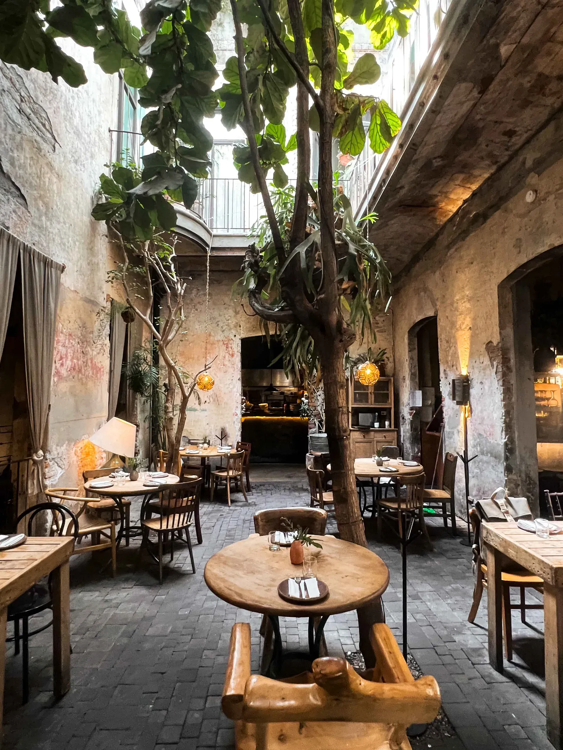 A restaurant with tables and chairs in a courtyard with a tree in the middle.