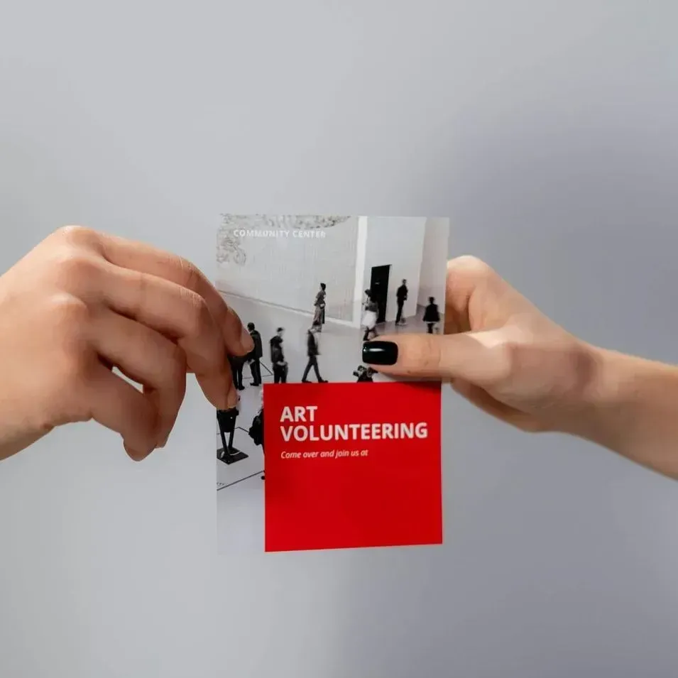 Two hands holding a brochure that says art volunteering
