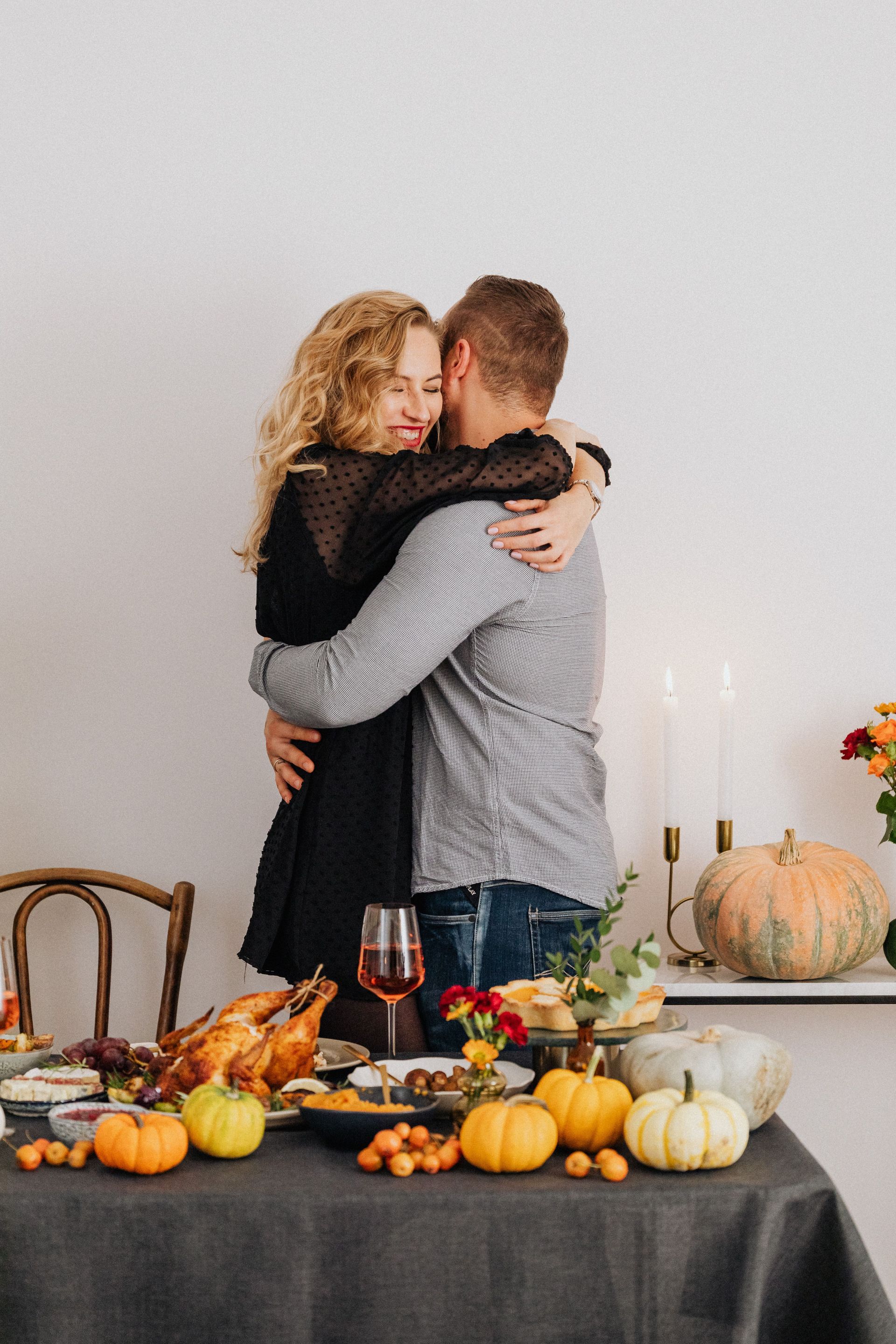Couple hugging by a table of pumpkins and autumn decorations in a cozy indoor setting