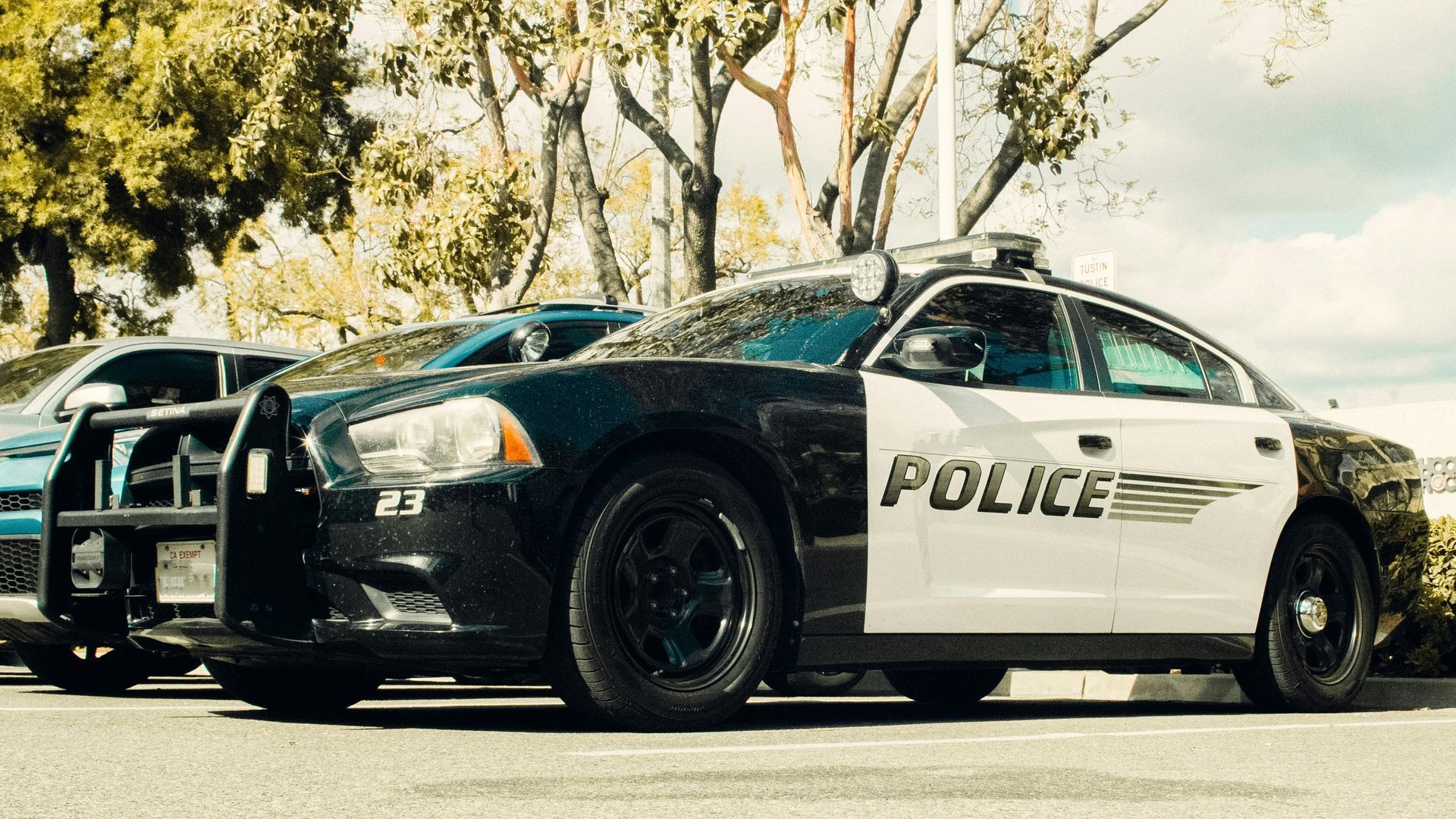 A black and white police cruiser parked in an outdoor lot on a sunny day.