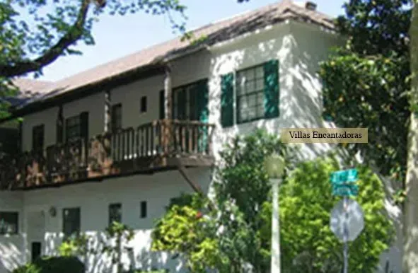 A white house with green shutters and a sign that says villa escalades