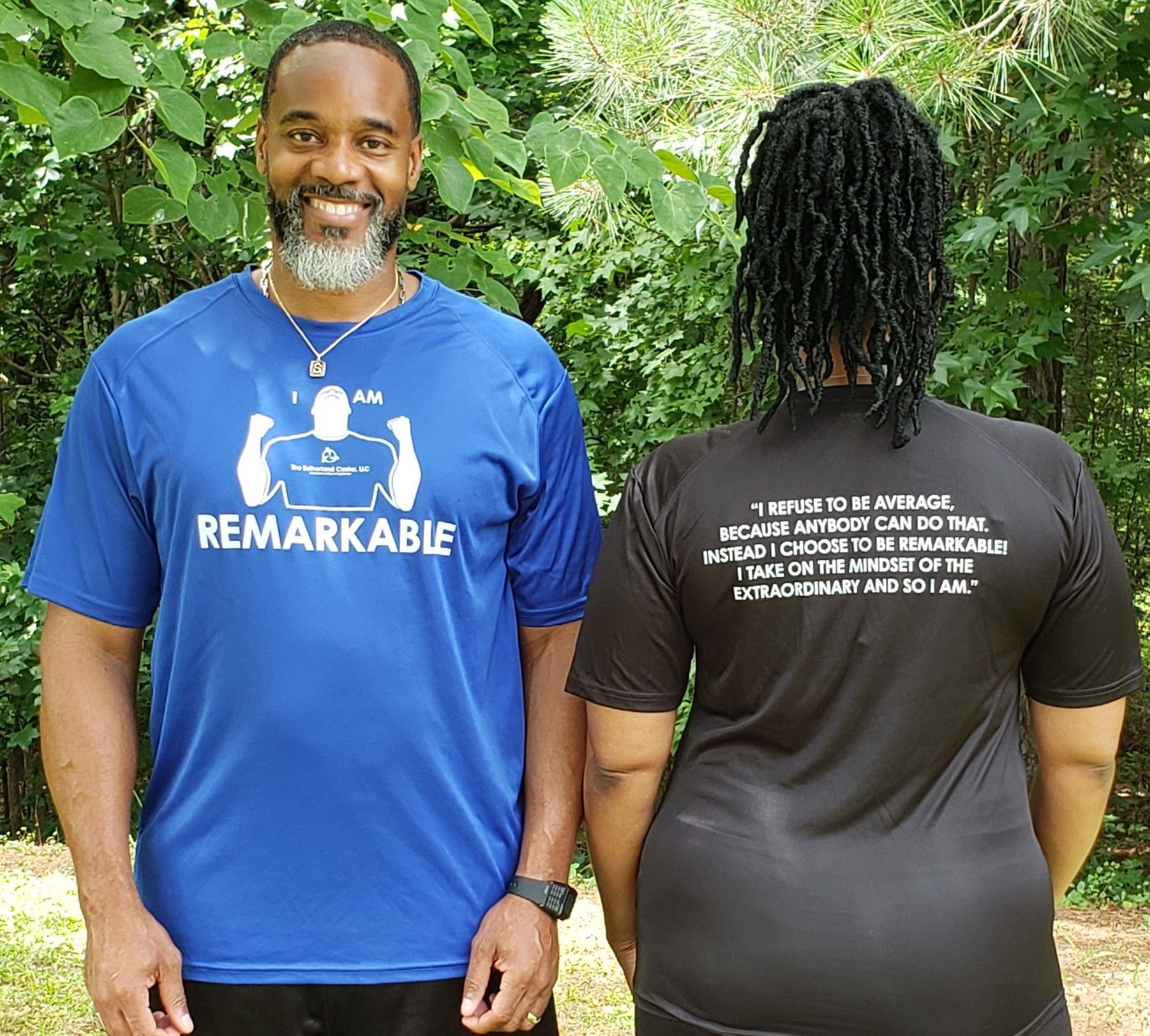 Two people modeling a blue shirt and a black shirt outdoors, one facing front and one showing the back.
