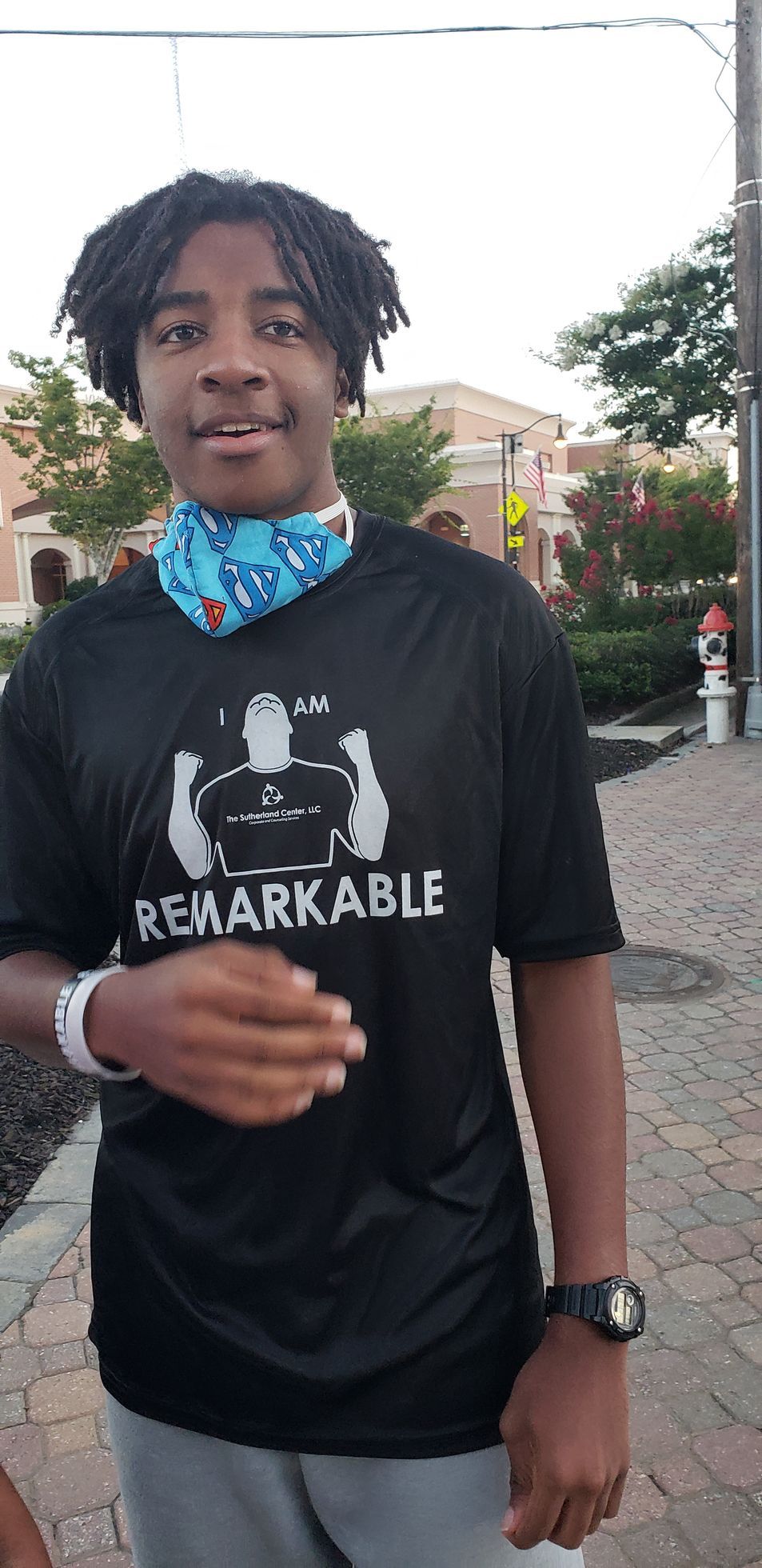 Person standing outdoors in a black shirt and blue neck gaiter, smiling at the camera.