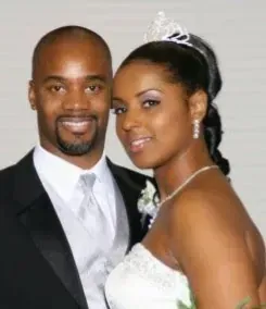 Couple smiling at their wedding, wearing formal black-and-white attire and a tiara.