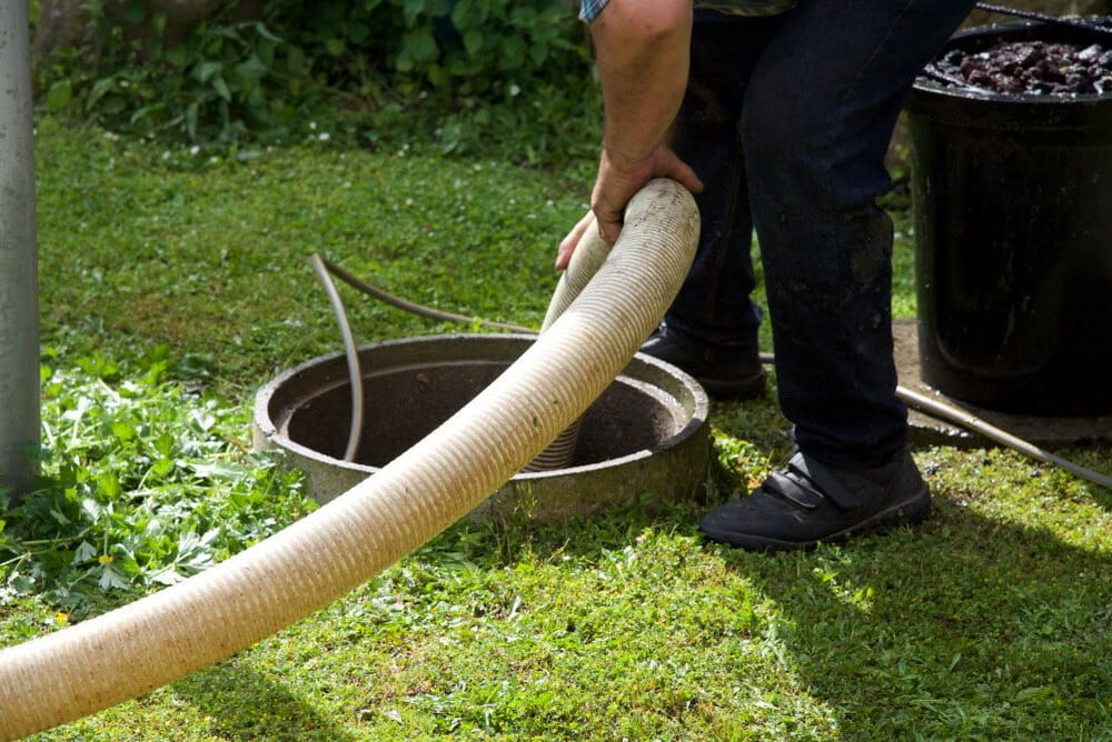 A Man is Pumping Water Into a Septic Tank With a Hose — Daniel Gray Plumbing in South Murwillumbah, NSW