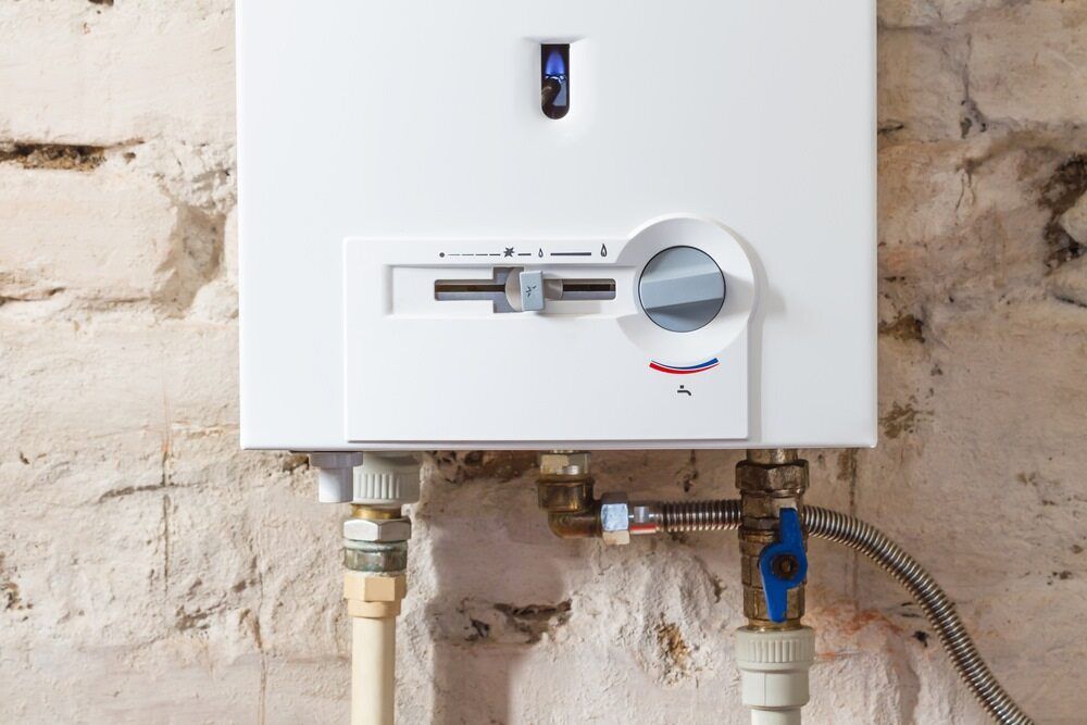 A White Water Heater is Attached to a Brick Wall — Daniel Gray Plumbing in Tweed Heads, NSW