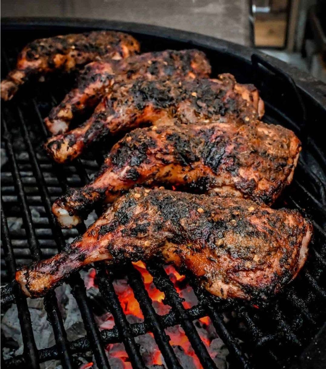 Grilled barbecue chicken pieces sizzling over glowing charcoal on a barbecue grill