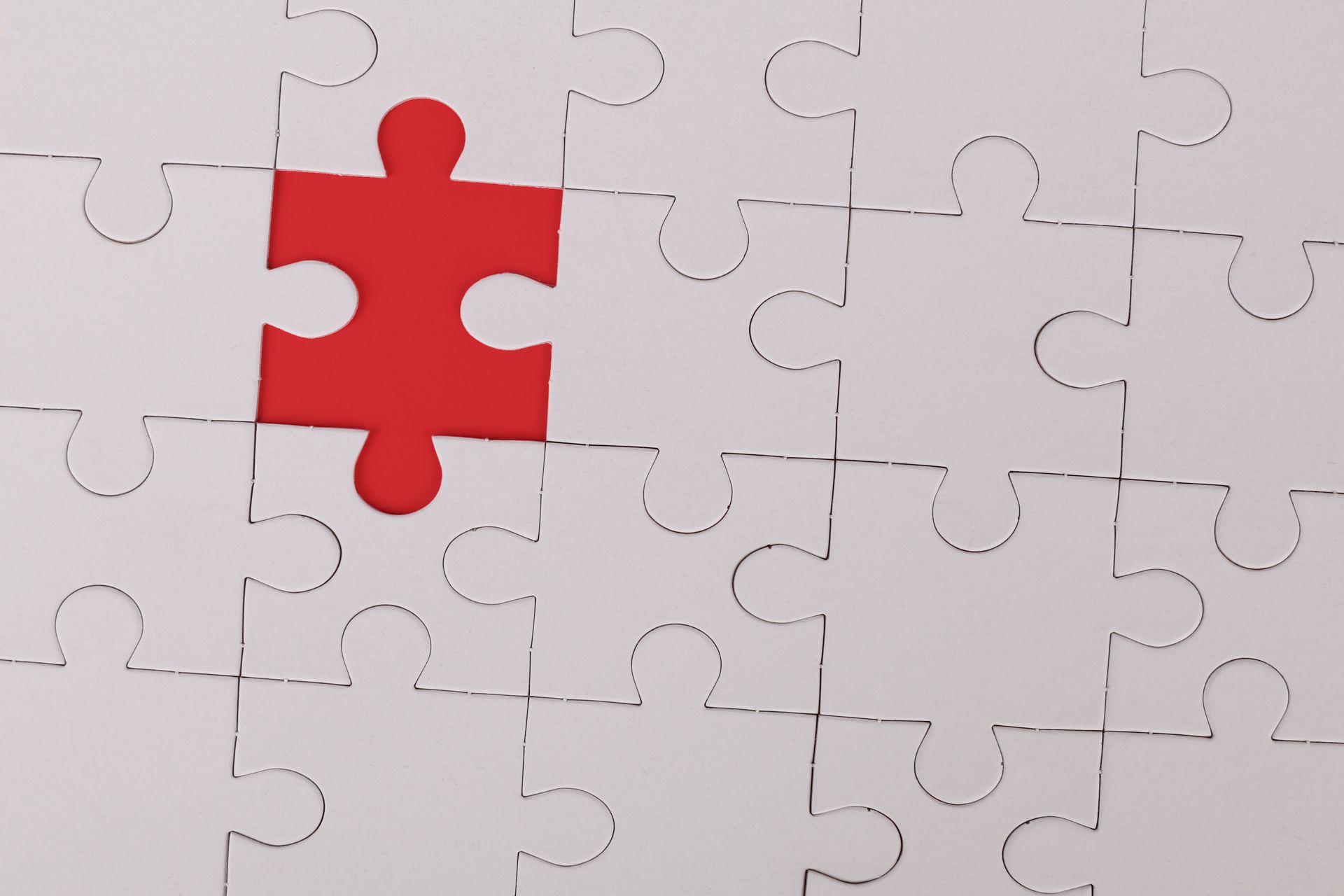 White jigsaw puzzle with a missing piece, revealing a red space.