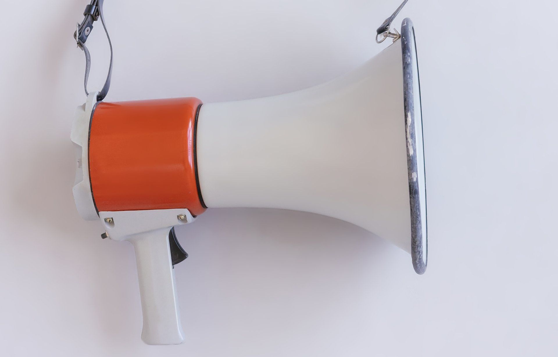 Orange and white megaphone hanging on a white wall.