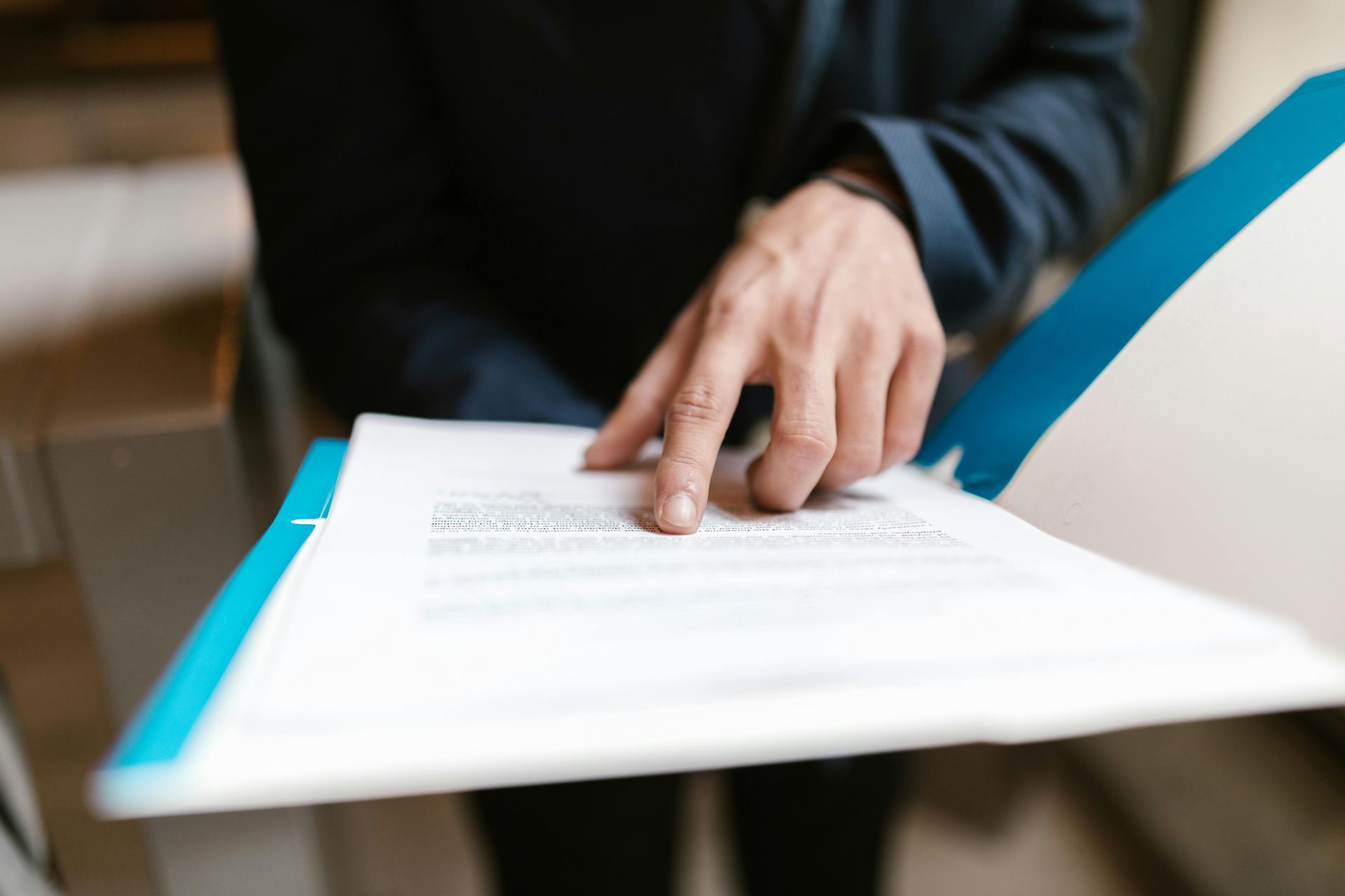 Close-up of a hand pointing at text on a business document in an office environment.