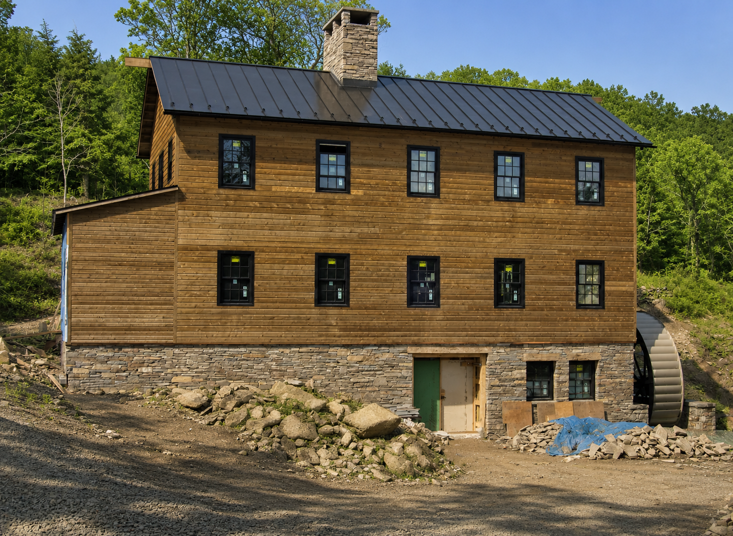 Wood-sided house on a snowy hillside with a dark roof and stone chimney