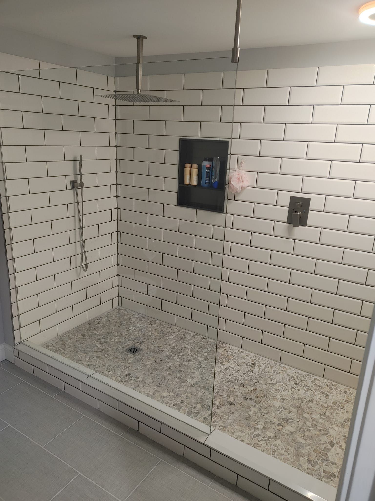 Modern tiled walk-in shower with rainfall showerhead, handheld sprayer, and wall-mounted control panel